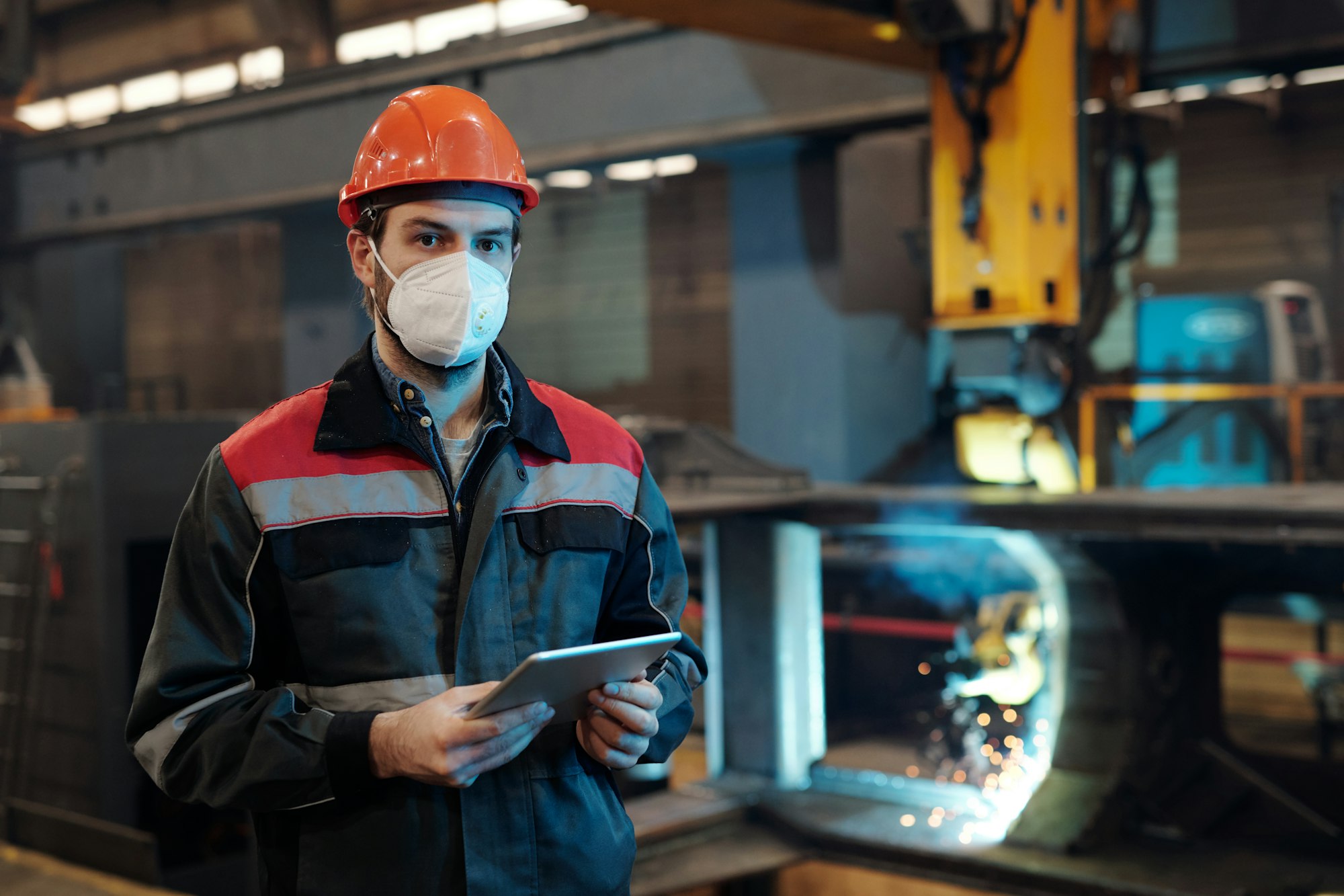 Contemporary factory engineer in protective workwear holding digital tablet