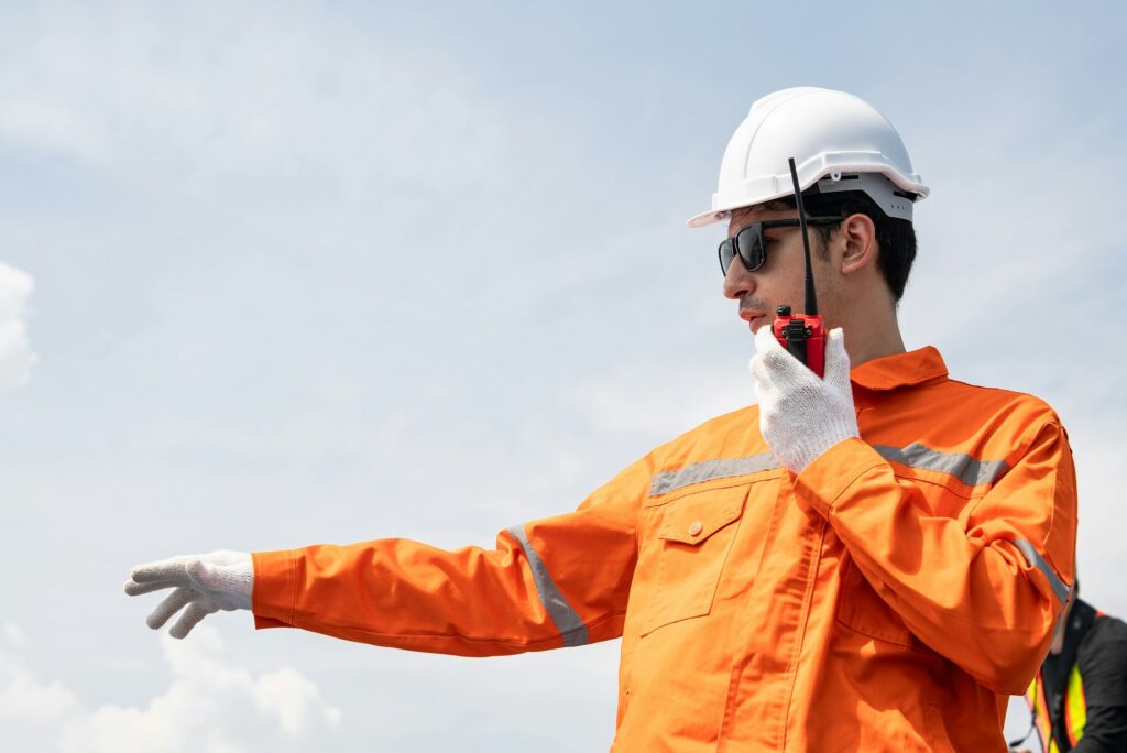 Male engineer in protective work wear talking on walkie talkie with colleague.