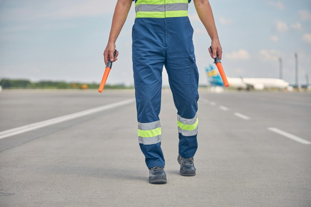 Signalman in workwear walking across the runway