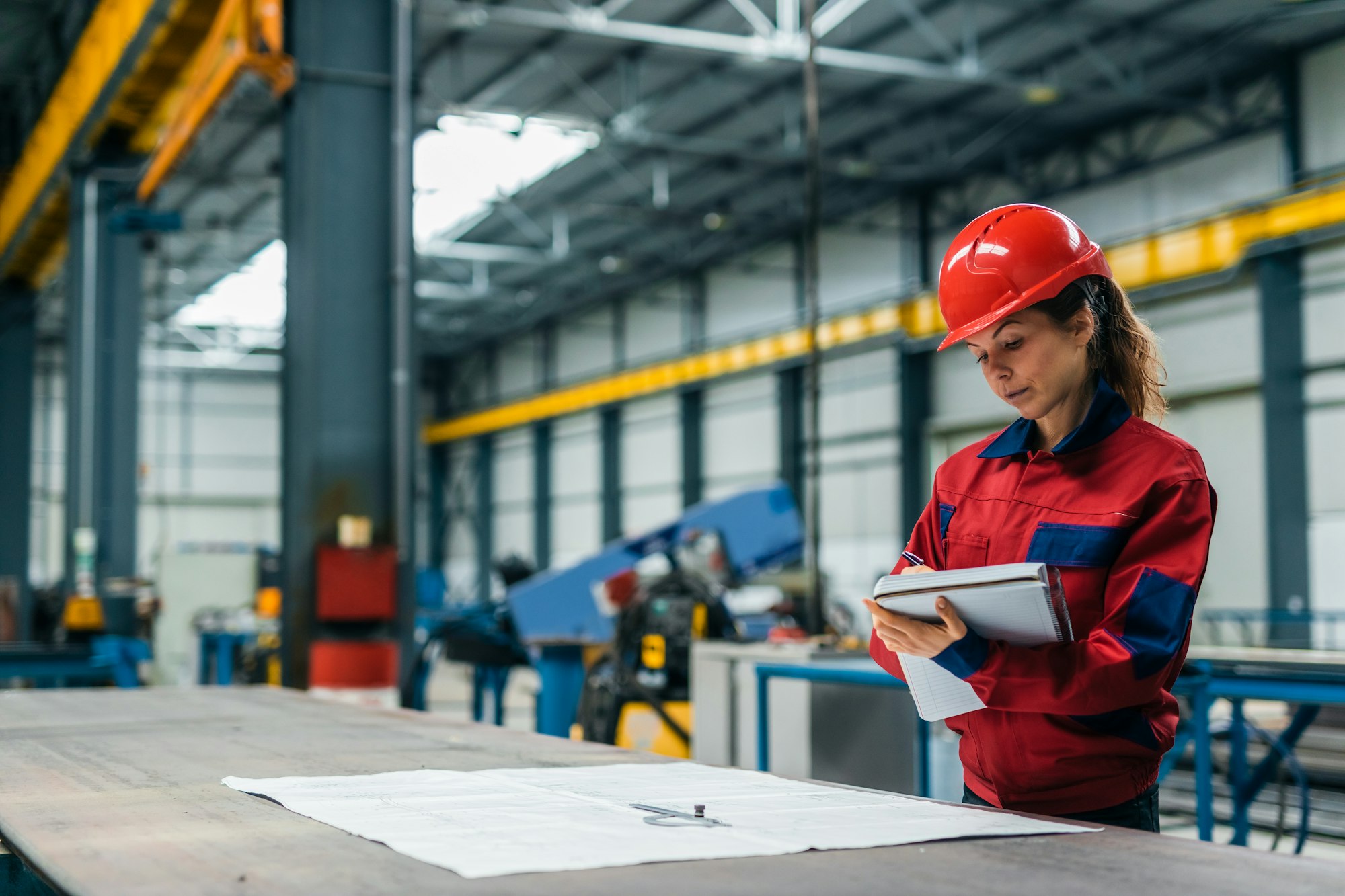 Woman in protective work wear looking at blueprints.