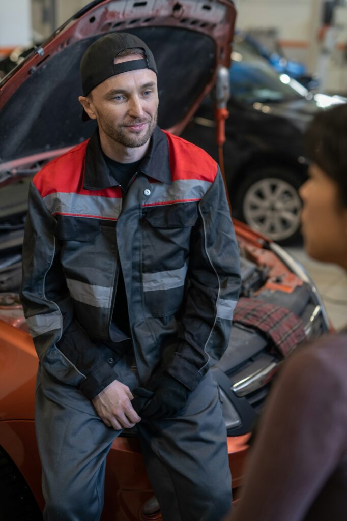 Young contemporary automechanic in workwear listening to female colleague